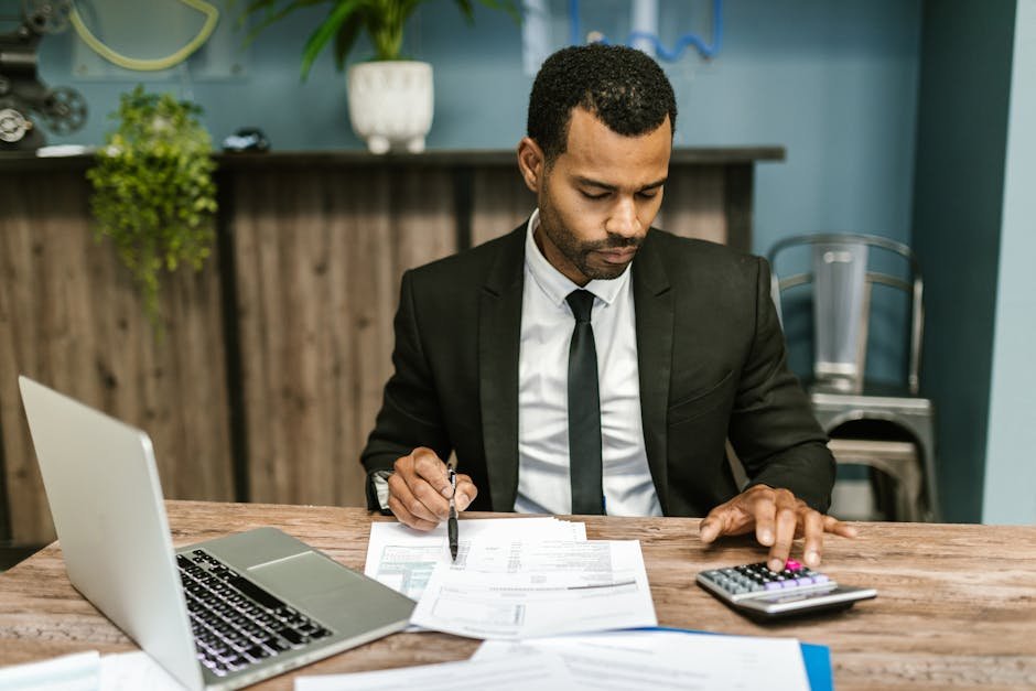 A focused businessman works with a calculator and documents in a modern office.